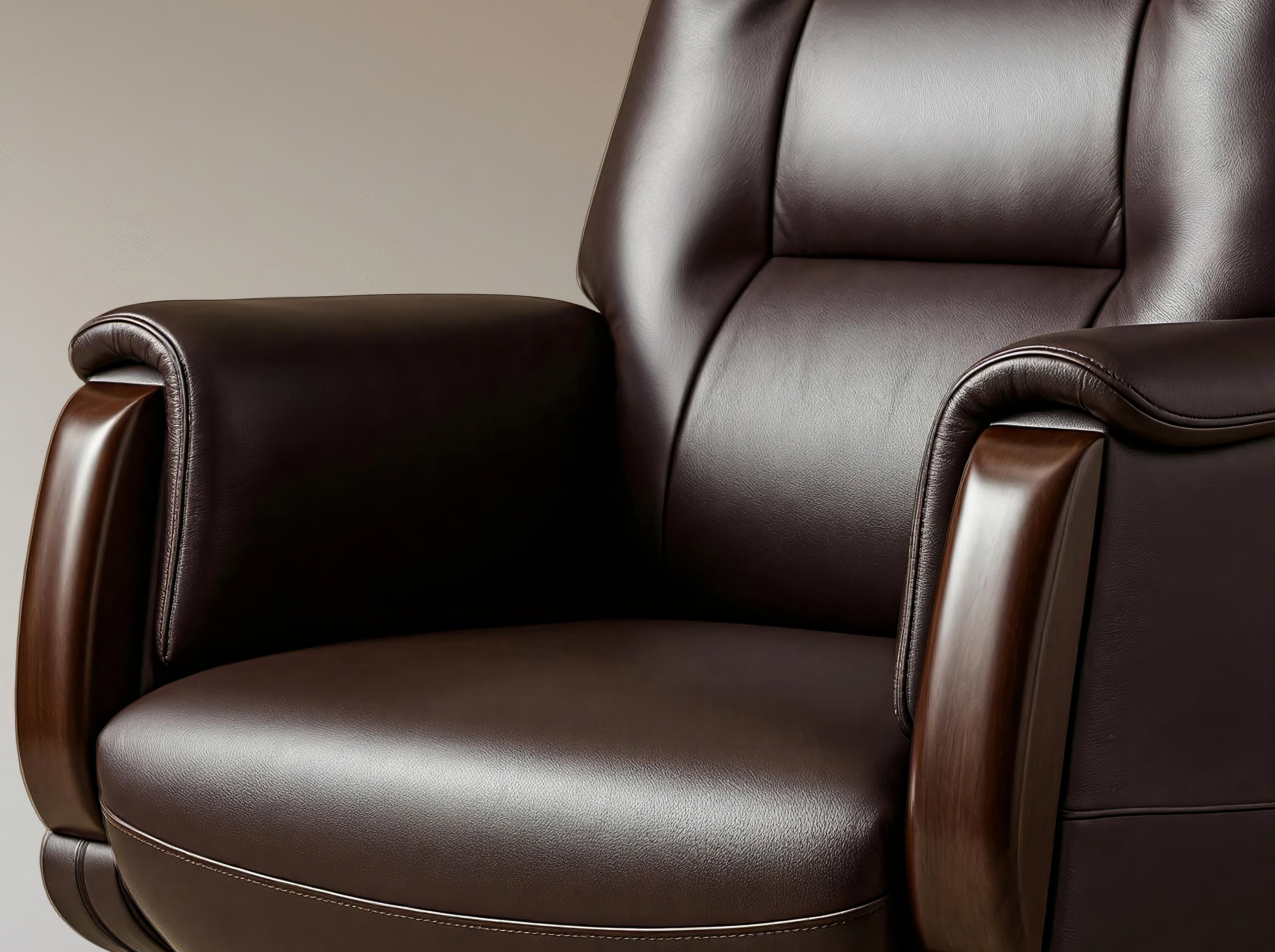 Close-up of a dark brown leather recliner chair with padded armrests and a high back, shown against a plain beige background.