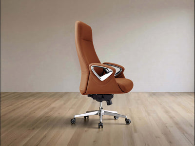 A modern high-back office chair upholstered in warm brown leather with a silver metal frame and five-wheel base, set against a minimalist beige wall and light wood floor.