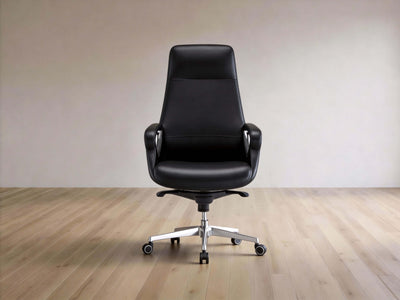 A modern black leather office chair with a high back, armrests, and a chrome five-star wheeled base, set against a minimalist beige wall and light wood floor.