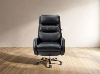 A black leather high-back office chair with a five-star metal base and casters, set against a minimalist beige wall and light wood floor.