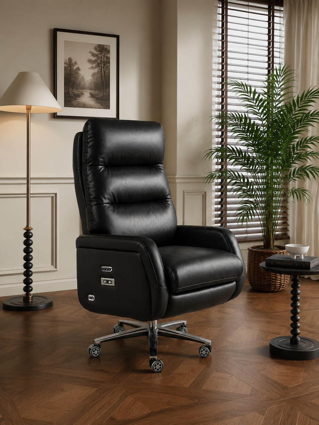 A black leather high-back office chair with a silver five-star wheeled base, shown in a styled home office setting with a floor lamp, window blinds, and a potted plant.