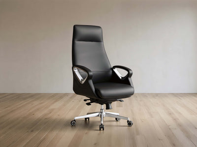A black leather high-back office chair with chrome armrest supports and a five-star wheeled base, set against a minimalist beige wall and light wood floor.