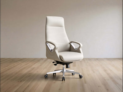 A modern high-back office chair upholstered in light beige leather, featuring chrome armrests and a five-star metal base with casters, set against a minimalist beige wall and light wood floor.