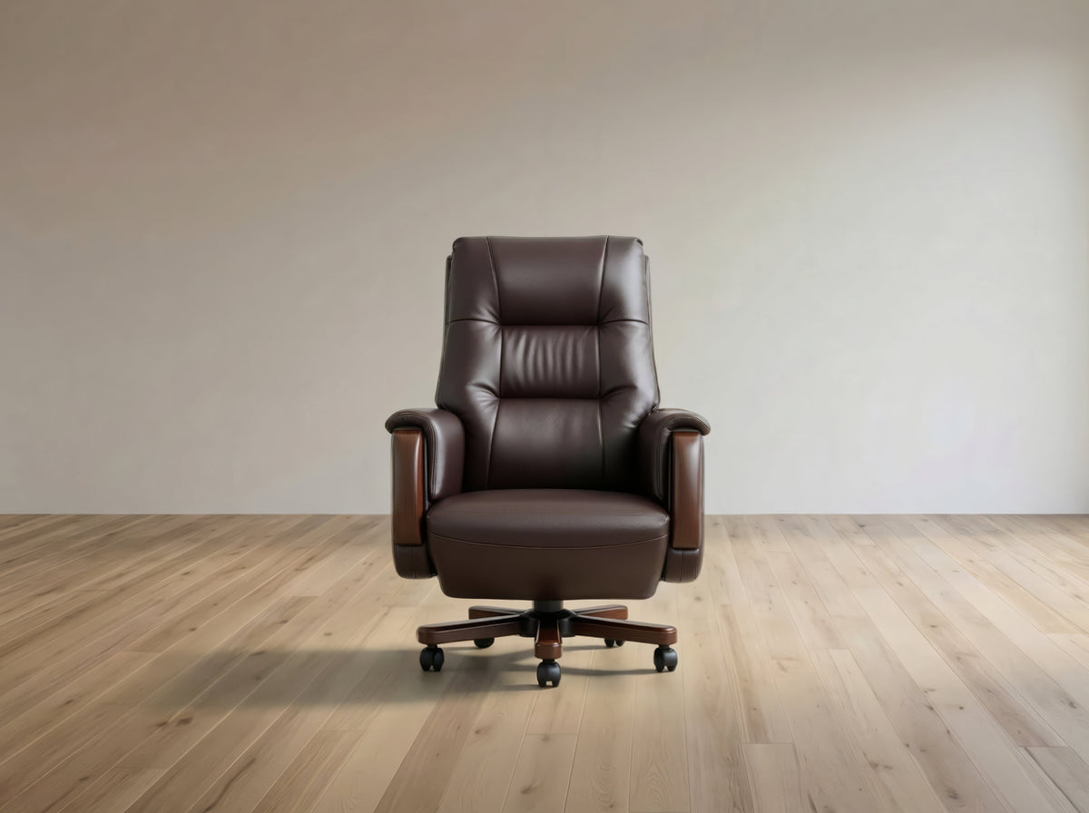 A dark brown leather office chair with a high back, padded armrests, and a five-star wheeled base, positioned in front of a plain beige wall on a light wood floor.